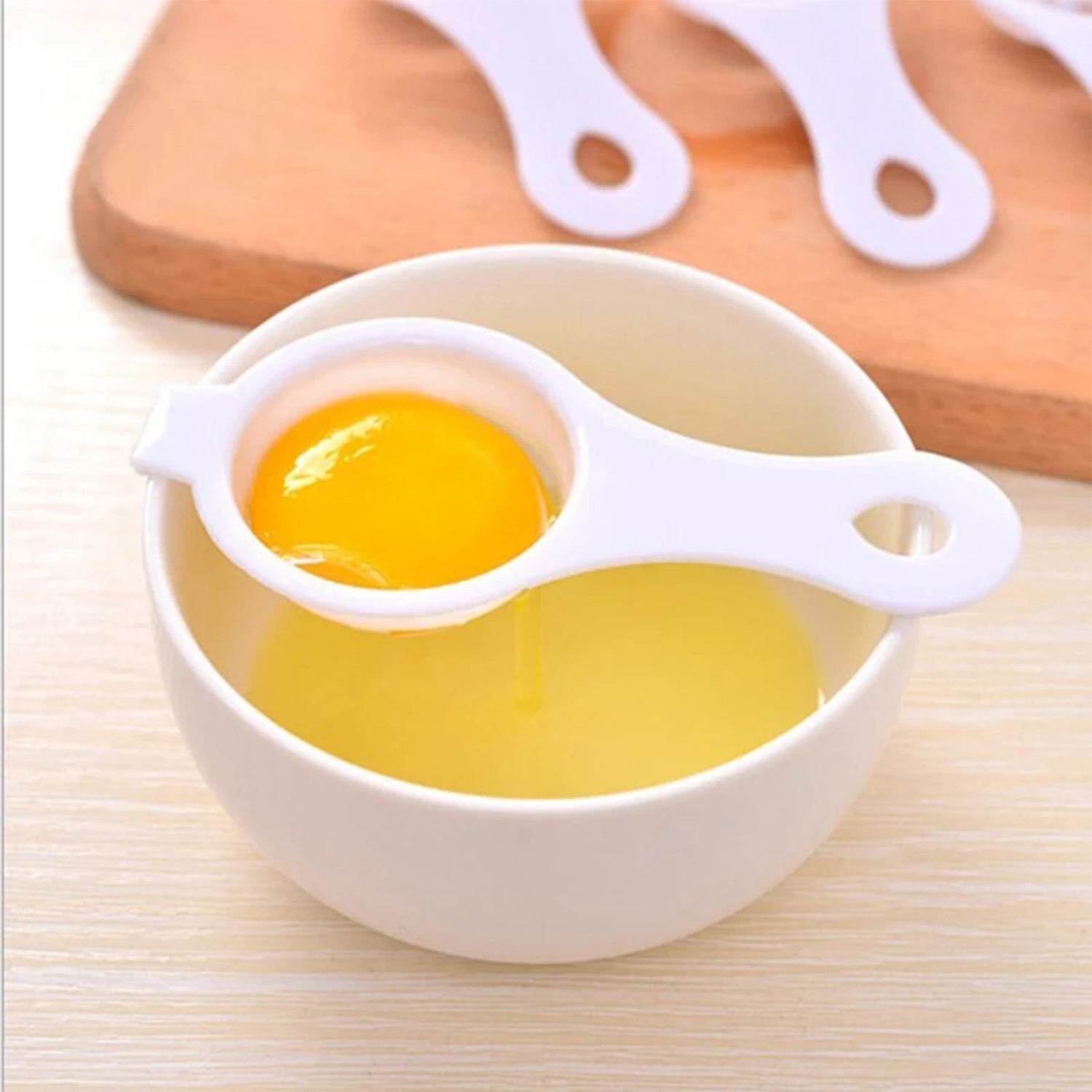 Bachat Club white plastic egg yolk separator tool resting on a bowl separating egg yolk from egg white