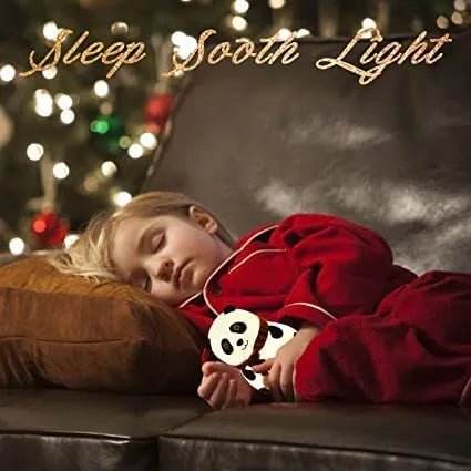 Child sleeping on couch holding Bachat Club panda night light LED glowing softly in dim room